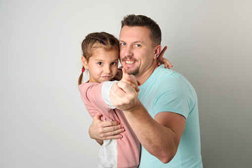 Happy young father hugging his daughter. Playful dad with his child, white background