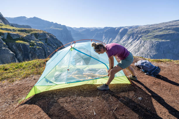 istock Woman setting up tent outdoors in Norway, spectacular view 1470249017