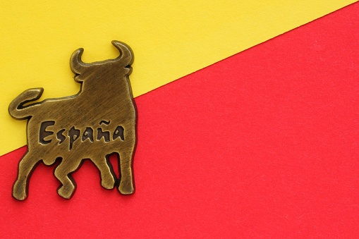 Metal souvenir fridge magnet of bull with word Spain on spanish on red and yellow background. Travel memory concept.