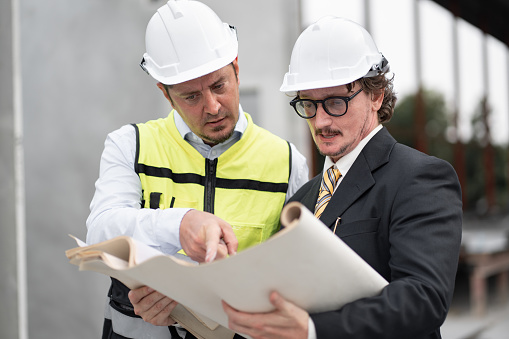 Portrait caucasian engineer man in suit with team engineer holding paper work at precast site work