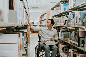 Asian handicapped man with wheelchair in library.