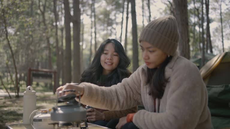 Two Young woman make coffee in the pinetrees forest in the morning.