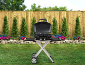 BBQ grill in a backyard with green grass and wood fence