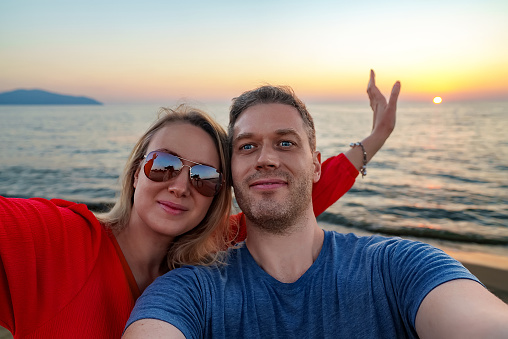 Guy and a girl take a selfie at sunset by the sea.