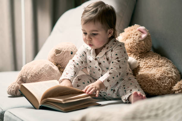 istock A little baby sitting on the sofa reading book 1470261329