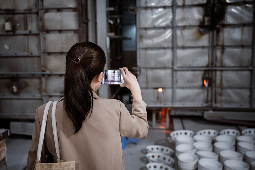rear view on woman taking photo of oven in ceramics factory