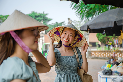 two vietnamese woman buying straw hats in village in north vietnam