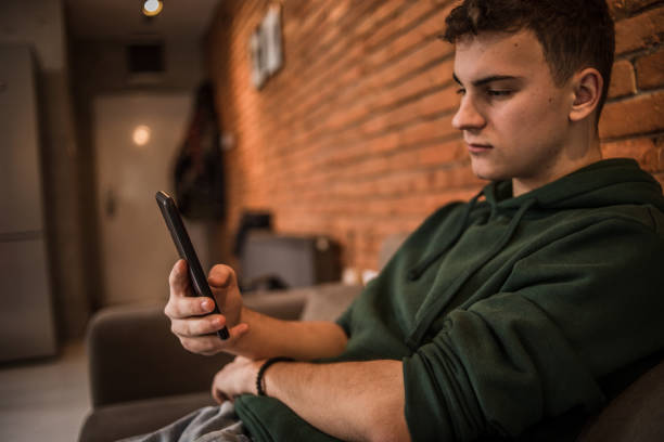 istock One man, Photo of a young man using a mobile phone while on the couch at home 1470263311