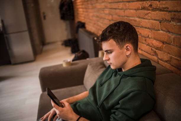 istock One man, Photo of a young man using a mobile phone while on the couch at home 1470263373