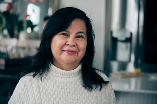A portrait of a mature aged Mexican Hispanic woman, in a home.