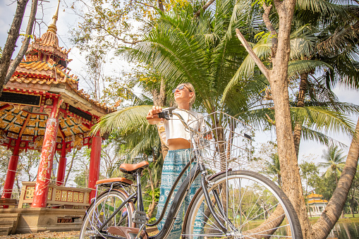She walks with the bike, temple behind her