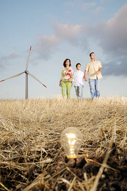 familie und windturbinen, die glühbirne in den boden - light bulb blue energy fuel and power generation stock-fotos und bilder