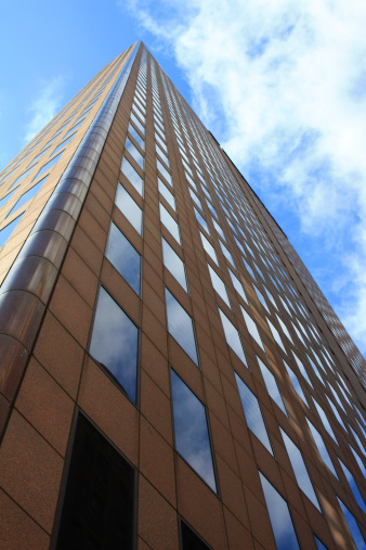 A tall brown Office Building in downtown Columbus, Ohio USA under a bright blue and cloudy sky.