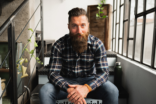 Portrait of hipster man looking at camera.Guy sitting on stairs with confident face.