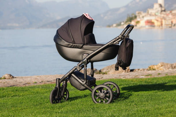 A modern black stroller on grass with lake background A modern black stroller on grass with lake background. baby stroller stock pictures, royalty-free photos & images