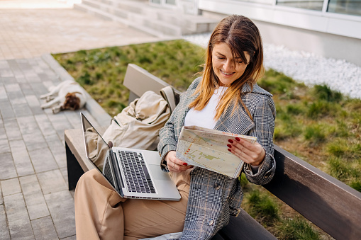 Woman is looking at a city map and sitting on a bench