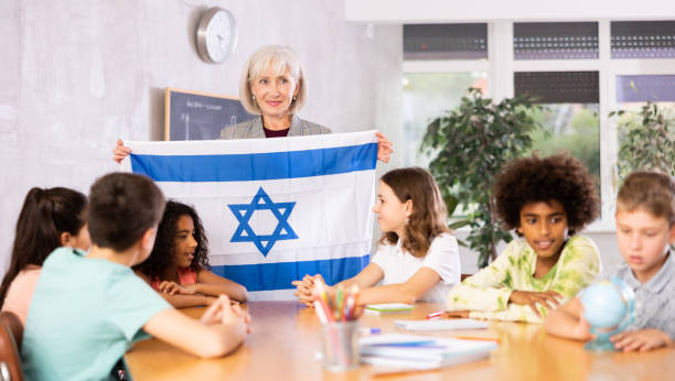 students listen to teacher who talks about Israel at entertaining geography lesson, children look at flag of Israel and listen to teacher s story about this country delta 8 thc eu stock pictures, royalty-free photos & images