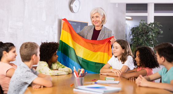 in classroom, positive woman teacher introduces children to concept and history of LGBT community