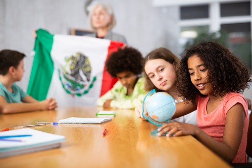 in  geography lesson, students carefully listen to woman teacher who talks about MexicÐ¾