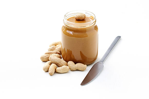 istock Peanuts next to jar of peanut butter and knife 147028283