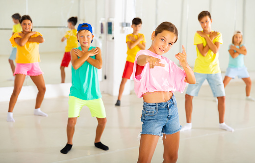 Portrait of preteen girl practicing hip-hop movements during group dance lesson in studio