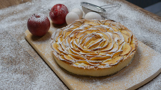 homemade apple pie, with red apples and eggs on wood background