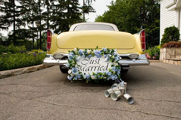 Bumper of limousine with just married sign and cans attached