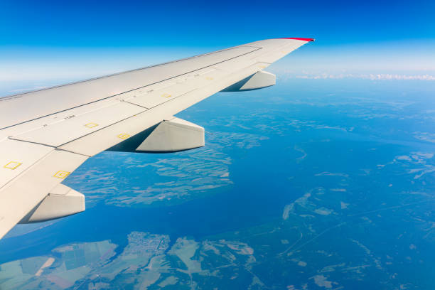 View from the airplane window at a beautiful cloudy sky and the airplane wing. Earth and sky as seen through window of an airplane.