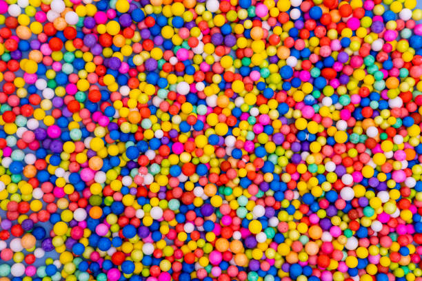 散在する色とりどりの丸いキャンディー、糖衣錠の明るい背景。砂糖菓子。楽しい休日。子供のお菓子。