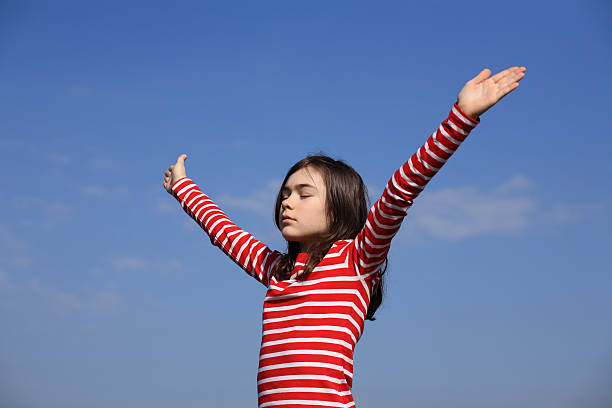 istock Girl holding arms up against blue sky 147029689