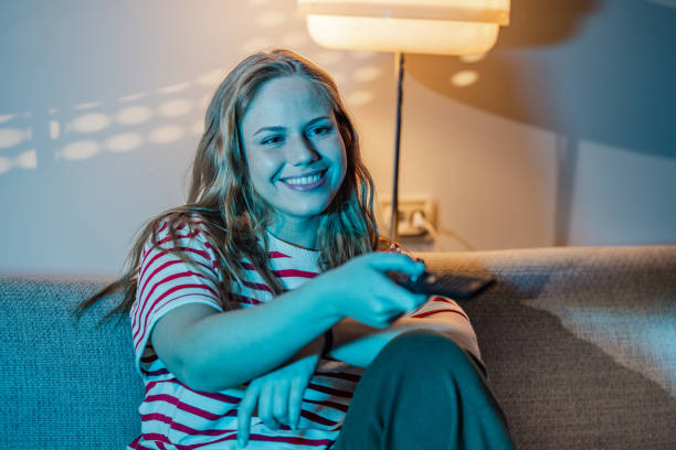 istock A young smiling woman relaxing at home while watching TV 1470299566