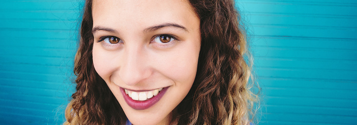 Looking deep into the lens, a radiant young woman smiles.