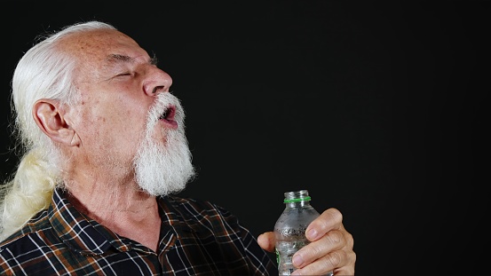 Old White Haired Man is Drinking Water From Plastic Bottle Photo