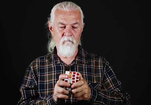 Old Man is Playing with Puzzle Cube Game
