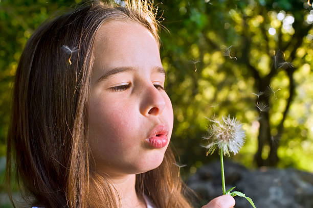 istock girl blowing a dandelion 147030908