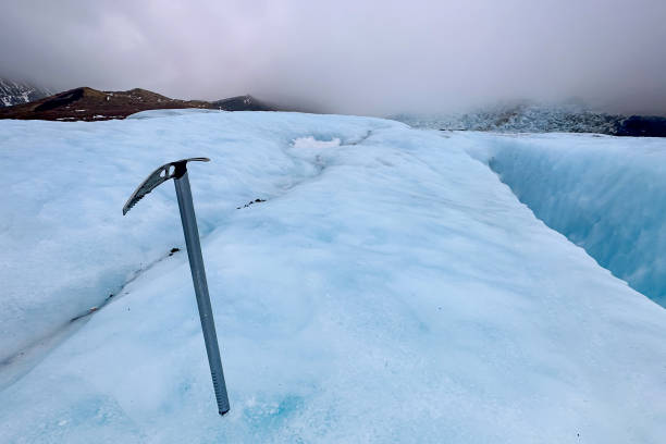 Ice ax planted onglacial surface on a cloudy day in the mountains