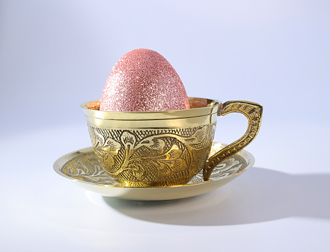 A Shimmering Pink Easter Egg in a Graceful Golden Teacup