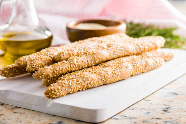 istock Italian grissini bread sticks with sesame seeds on white cutting board. 1470317402