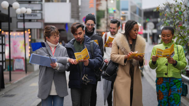 Multi-racial group of tourist friends exploring city with local tour guide in Tokyo A multi-racial group of tourist friends are exploring the city with a local tour guide in Tokyo. short weave hairstyles stock pictures, royalty-free photos & images