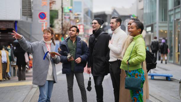 Multi-racial group of tourist friends exploring city with local tour guide in Tokyo A multi-racial group of tourist friends are exploring the city with a local tour guide in Tokyo. short weave hairstyles stock pictures, royalty-free photos & images