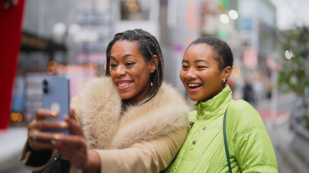 две подруги-туристки делают селфи и снимают видео во время прогулки по городу в харадзюку токио - braided women african descent winter стоковые фото и изображения
