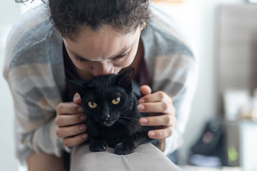 Latin woman petting black pet cat