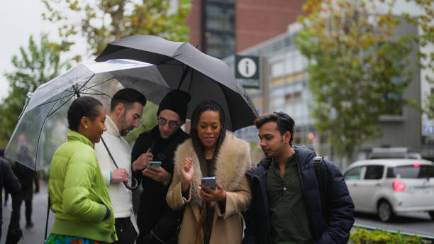 gruppo multirazziale di amici turisti che utilizzano lo smartphone per esplorare la città di harajuku tokyo - candid women african descent umbrella foto e immagini stock