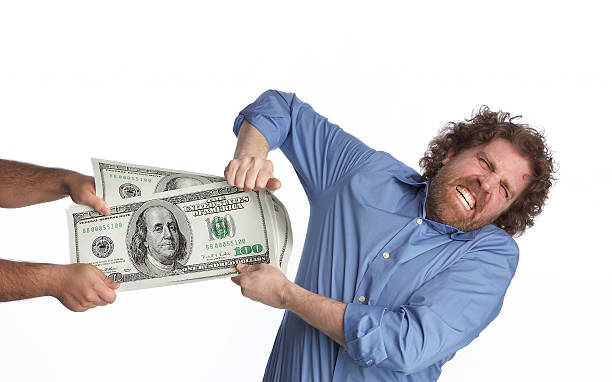 A man comically playing tug of war with hundred dollar bill Tug of War with Big Money government large currency finance stock pictures, royalty-free photos & images