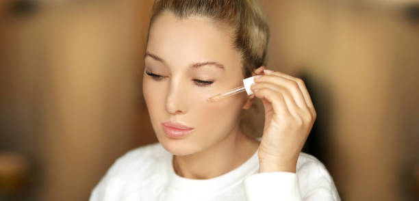 istock woman applying serum, lotion to her face 1470325611