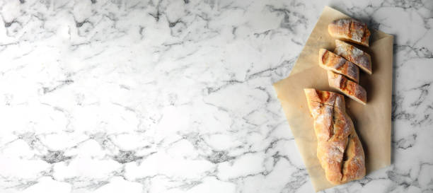 istock Tasty bread on white marble table, top view with space for text. Banner design 1470326639