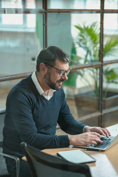 istock Busy man sitting at his desk, working on a laptop while typing 1470326783