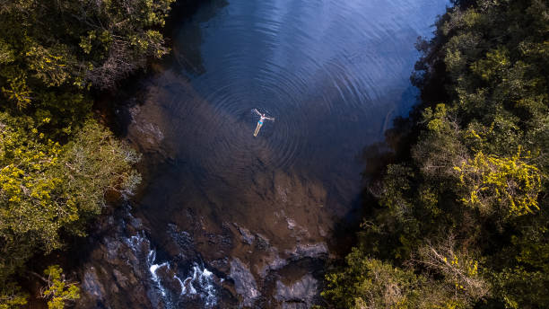 istock Woman floating on the water after a waterfall 1470327202