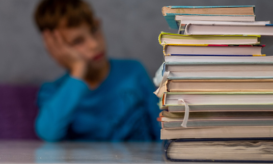 A boy is doing his homework and is getting annoyed because he has a lot to do.