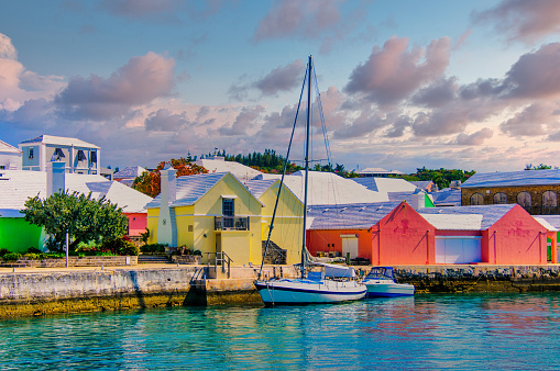 Two small boats are docked in St. George, Bermuda in front of colorful buildings.
